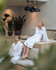 Entspannung in der Kaminlounge im Heaven Spa Entspannende Personen in Bademänteln in der Kaminlounge, Heaven Spa
