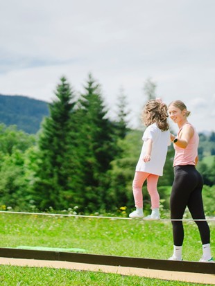 Balancieren auf der Slackline-Bank zur Zirkuswoche im Naturresort Puradies, Leogang, Salzburger Land Kind balanciert auf Slackline-Bank, Puradies Leogang