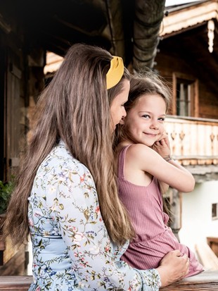Eine Frau, ein Mädchen und ein Mann, mit dem Chaletdorf Puradies im Hintergrund.