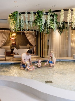 Zwei Erwachsene und ein kleines Kind im Kinderpool des Naturresorts Puradies.