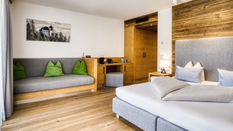 Sitzbank und Doppelbett mit Kleiderschrank in der Deluxe Suite im Naturresort Puradies Sitzbank und Doppelbett mit Kleiderschrank in der Deluxe Suite im Naturresort Puradies