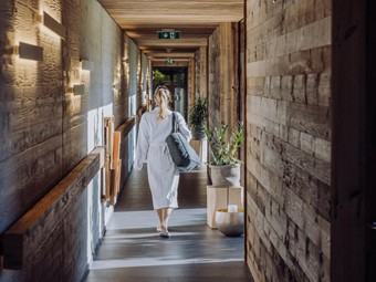 Gang zum Saunahaus im Naturresort Puradies, Leogang Person im Bademantel im Gang zum Saunahaus, Puradies Leogang