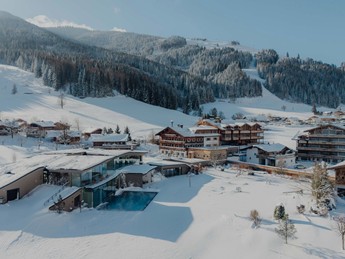 Aerial view of whole resort in winter with ski slope in background, Puradies Leogang