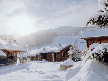 Snow-covered path between chalets in sunshine, Puradies Leogang