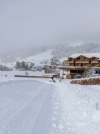Naturresort Puradies im Winter mit präparierter Skipiste Präparierte Skipiste vor dem winterlichen Naturresort Puradies, Leogang