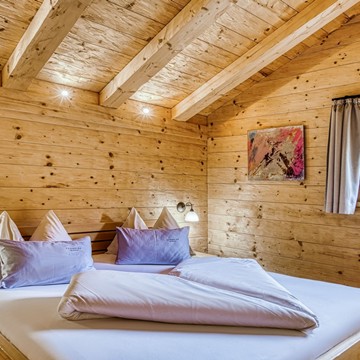 Schlafzimmer im Privat Spa Chalet Plus des Puradies Leogang Schlafzimmer im Privat Spa Chalet Plus des Naturresorts Puradies mit Holzwänden und Holzdecke.