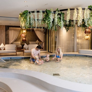 Zwei Erwachsene und ein kleines Kind im Kinderpool des Naturresorts Puradies.