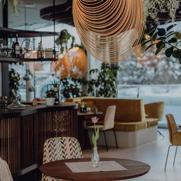 Innenansicht des Gourmetrestaurants Essenz im Naturresort Puradies, mit eleganter Einrichtung und gedeckten Tischen.
