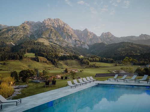 Infinity Pool mit Liegestühlen und Blick auf die Leoganger Steinberge im Naturresort Puradies.