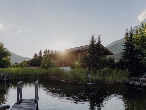 Naturbadeteich mit Saunahaus im warmen Abendlicht – Naturresort Puradies, Leogang, Salzburger Land Naturbadeteich mit Saunahaus im Abendlicht, Puradies Leogang