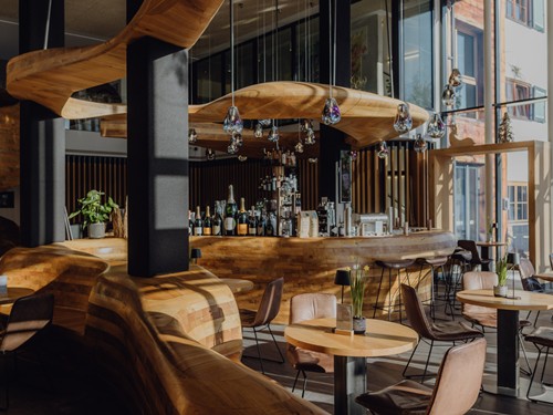 Geschwungene Holzbar der Bar Freiraum mit stimmungsvoller Beleuchtung im Naturresort Puradies in Leogang.