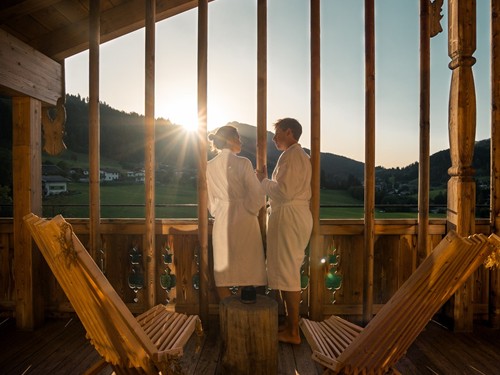 Two people in bathrobes on a balcony at sunset at Naturresort Puradies