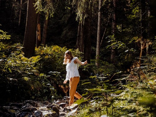 Barefoot Through the Stream – Forest Walk near Naturresort Puradies in Leogang, Salzburger Land Person walking barefoot across a forest stream at Naturresort Puradies in Leogang