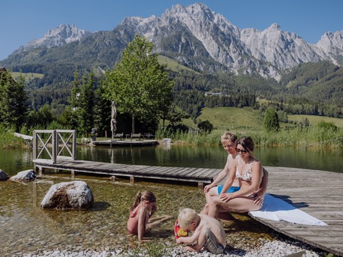 Familie am Steg des Naturbadeteichs im Naturresort Puradies, Leogang