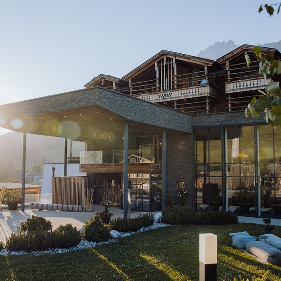Haupteingang des Naturresorts Puradies in Leogang im Sommer, mit grünen Wiesen und dem einladenden Vorplatz.