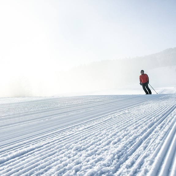 Skifahrer fährt im Winter auf präparierter Piste.
