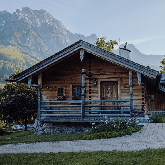 Chalet im Naturresort Puradies im Sommer, umgeben von grünen Wiesen und Bergen im Hintergrund.