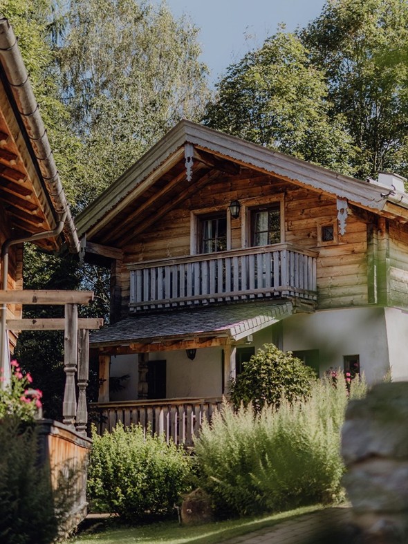 Chalet im Sommer, umgeben von grüner Landschaft.